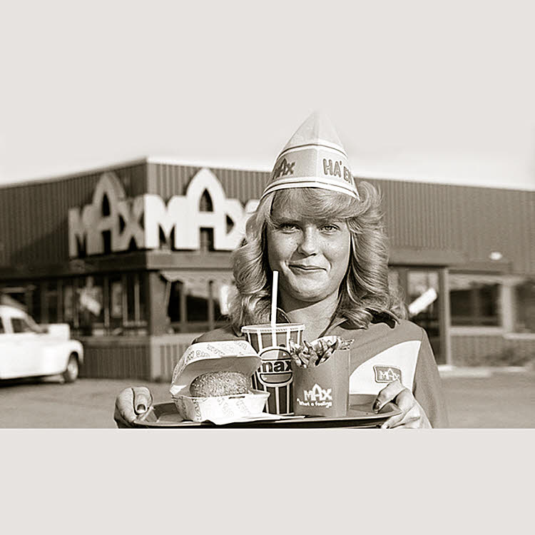 Svartvit bild på servitris som håller i en bricka med hamburgermeny utanför MAX på 60-talet. Foto.